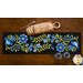 The completed Baltimore Garden Table Runner in Periwinkle, staged on a wooden table with four black chairs and a loaf of bread on a serving plate.