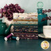 A stack of the fabrics included in the Ophelia collection, with flowers and a vase and a teapot and teacup and a bottle and thread.