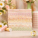 A stack of the fabrics included in the Dear Daisy collection, with flowers and jars and a mug.