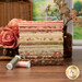 A stack of the fabrics included in the Collection for a Cause - Heirloom, with flowers and a window and a bottle and a basket and thread.