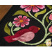 A super close up on the appliqué of the runner, demonstrating fabric colors and topstitching details on the flowers, leaves, and bird.