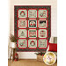 The completed Holiday Cheer Panel Quilt, colored in black, cream, red, and green fabrics, hung on a cream shiplap wall and staged with coordinating furniture and décor.