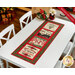 The completed Holiday Cheer Table Runner, colored in black, cream, red, and green fabrics, staged on a white table in a festive space.