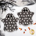 The two completed Ghostly Hot Pads, colored in gray and white glow in the dark fabrics from the Frank and Friends collection, staged on a white table with coordinating décor and candy corn.