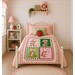 The completed quilt, staged on a pink bed in a child's room.