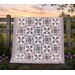 Patchwork quilt hanging on a wooden fence at sunset.