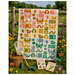Quilt hanging on a fence with a basket, net, binoculars, and wildflowers in a garden.