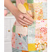 A close up on the front of the apron, where a model inserts a wooden spoon into the pocket.