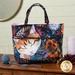 The completed Playing with Panels Market Tote, colored in orange, magenta, cyan, and black fabrics from the Calico Cat collection by Timeless Treasures, staged on a wooden armoire with coordinating décor.