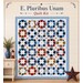 Mockup of the completed E. Pluribus Unum Quilt, a patchwork of dynamic shapes in patriotic colors on a cream background with text and props