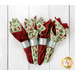 The four completed cloth napkins, colored in red, cream, and mint green fabrics from the Evergreen Wishes collection by Riley Blake Designs, staged on a white wooden surface.