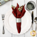A top down shot of the napkin with the red fabric facing out, staged on a coordinating table setting on a white wooden table.