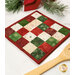 An angled shot of the Hot Pad, colored in red, green, and cream fabrics from the Christmastime collection by Maywood Studio, staged on a white marble kitchen counter with coordinating decor.