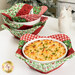 The four completed bowl cozies, colored in red, green, and white fabrics from the Barnyard Christmas collection by Northcott Fabrics, stacked with white bowls and staged on a white table with coordinating décor.