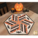 The completed 60 Degree Diamond Table Topper, colored in Halloween fabrics from the Purrs & Boos collection by Moda Fabrics, staged on a wooden table with coordinating candy corn and décor.