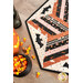A close up on one corner of the topper, demonstrating fabric print and colors details as well as two of the appliqué bat; coordinating décor peeks into frame from the left side.