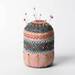 Colorful embroidered pincushion with pins stuck in the top, on a white background.