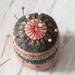 A top down shot of the pincushion, showing details on the embroidered stitching.