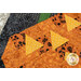 A super close up on the yellow appliqué of the jack-o'-lantern, demonstrating fabric colors and print details as well as top quilting effects.