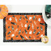 A top down shot of the placemat, showing details on the orange fabric with tossed Halloween monsters.