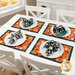 Lifestyle shot of a white dining table with the four Halloween-themed orange placemats, coordinating plates, and matching cloth napkins.