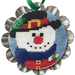 Jolly Snowman Tin Kit featuring a cross stitched snowman in a black hat with colorful winter details, framed in a silver tart tin with a green hanging ribbon.