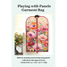 Front cover of the pattern showing the completed project colored in a vibrant poppy themed panel, staged on a hanger against a white shiplap wall with coordinating flowers.
