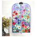 The completed project colored in a vibrant floral themed panel, staged on a hanger against a white shiplap wall with coordinating flowers.