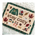 The completed Stay Cozy cross stitch project styled on a shag rug.
