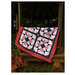 The completed project in red, white, and black fabrics, staged on a woodsy gazebo.