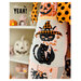 Close up on the appliqué black cat wearing a witch hat and a candy cane bow on a quilted background.