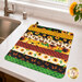 The completed Dry Ideas drying mat, colored in vibrant prints from the Sunshine Whispers collection by Wilmington Prints, staged on a marble kitchen counter with coordinating decor.