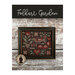 Front cover of the Folkart Garden cross stitch pattern finished in a rustic black frame hung on a wooden plank background.