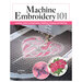 Machine Embroidery 101 book cover featuring an embroidery machine stitching a pink and white heart design with colorful embroidered samples.