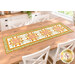 The completed Fancy Star Table Runner, colored in warm fabrics from the Sunflower Whispers collection by Riley Blake Designs, staged on a wood table.