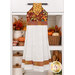 The completed Hanging Towel colored in warm autumnal fabrics from the Baskets of Autumn Blessings from Studio E Fabrics, staged on a kitchen drawer with coordinating décor.