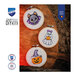 Three Halloween cross stitch projects with a ghost, bat, and pumpkin, staged on a rustic wood surface.
