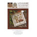 Front of pattern showing the completed cross stitch on a small ornament pillow staged on a table by autumnal sprigs.
