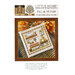 Front of pattern showing the completed cross stitch on a small ornament pillow staged on a table by autumnal sprigs.