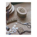 Small finished cross stitch pinkeep surrounded by a sewing roll, scissors, buttons, and other supplies.