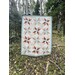 Colorful quilt with star patterns hanging outdoors in a wooded area.
