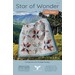 Quilt titled “Star of Wonder” hanging outdoors with mountain scenery in background.