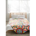 Colorful patchwork quilt on a bed with white pillows in a bright bedroom.