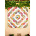Colorful geometric quilt pattern mounted on a beige wall beneath hanging green vines.