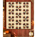 The completed Bear Hugs quilt, colored in warm flannels from the Flannel Season collection by Moda Fabrics, hung on a red barn wall with coordinating pumpkins and farm décor.
