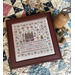The Oh Sweet Summer pattern finished and framed, staged on a quilt with coordinating decor and a spool of thread.