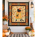The completed Retro Kitty Halloween Panel Quilt, colored in warm autumnal colors from the Spooky collection by Riley Blake Designs, staged on a white shiplap porch wall with coordinating décor and pumpkins.