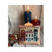 Finished Liberty Lane cross stitch pillow in front of a bundle of lit candles on a wooden plank background.