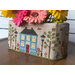 Decorative fabric box with a stitched house pattern holding colorful flowers.