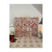 Finished cross stitch pattern on a decorative mat next to quaint lanterns and holly berries.